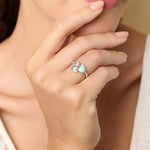 Woman wearing a ring with a blue gemstones, posing thoughtfully with hand on chin.