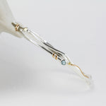 Silver bracelet with gold accents and gemstones on a white background