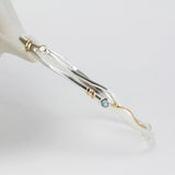 Silver bracelet with gold accents and gemstones on a white background