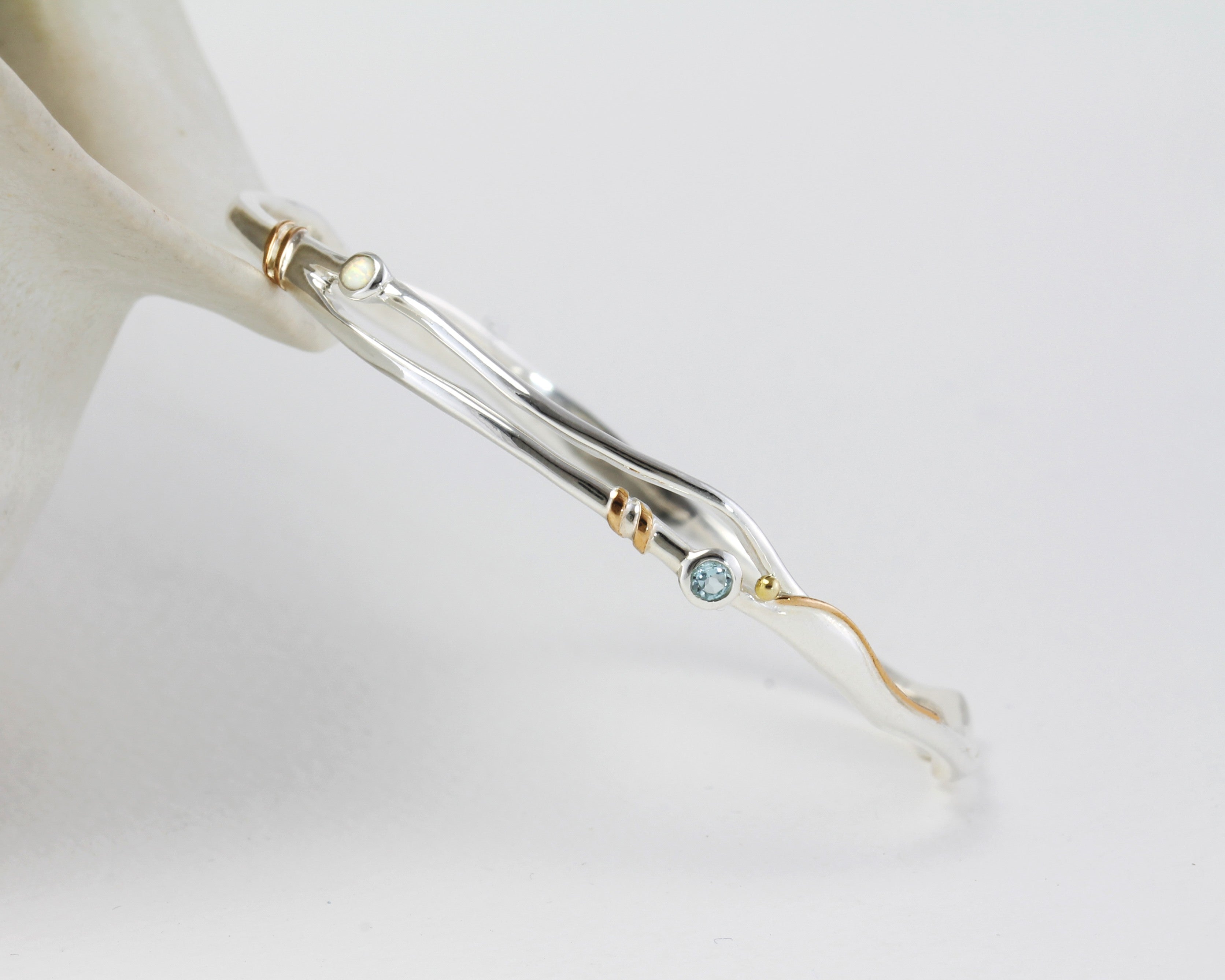 Silver bracelet with gold accents and gemstones on a white background