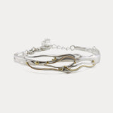 Mixed Metal Bracelet with a flowing design of sterling silver and 14kt gold with brass pip details.