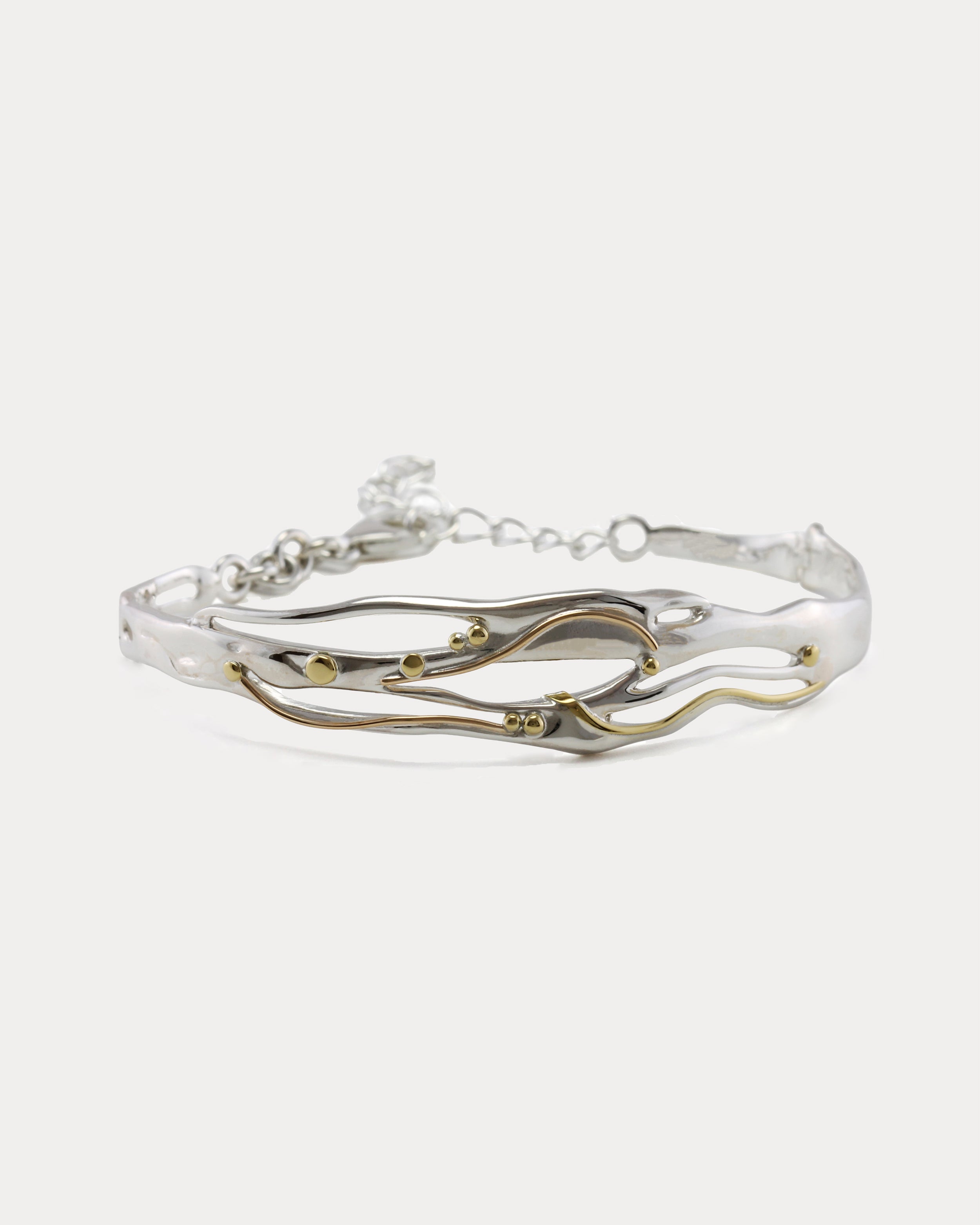 Mixed Metal Bracelet with a flowing design of sterling silver and 14kt gold with brass pip details.
