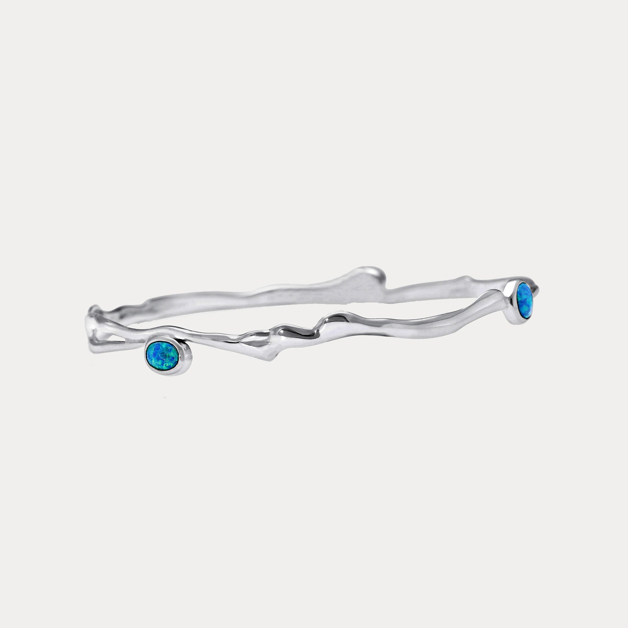 A Sterling Silver bangle bracelet with three Opal stones set in it, two blue and one white, against a white background.
