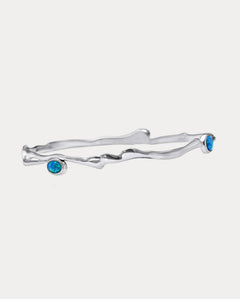 A Sterling Silver bangle bracelet with three Opal stones set in it, two blue and one white, against a white background.