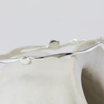 Silver bracelet with blue and white Opal gemstones on a white ceramic pot.