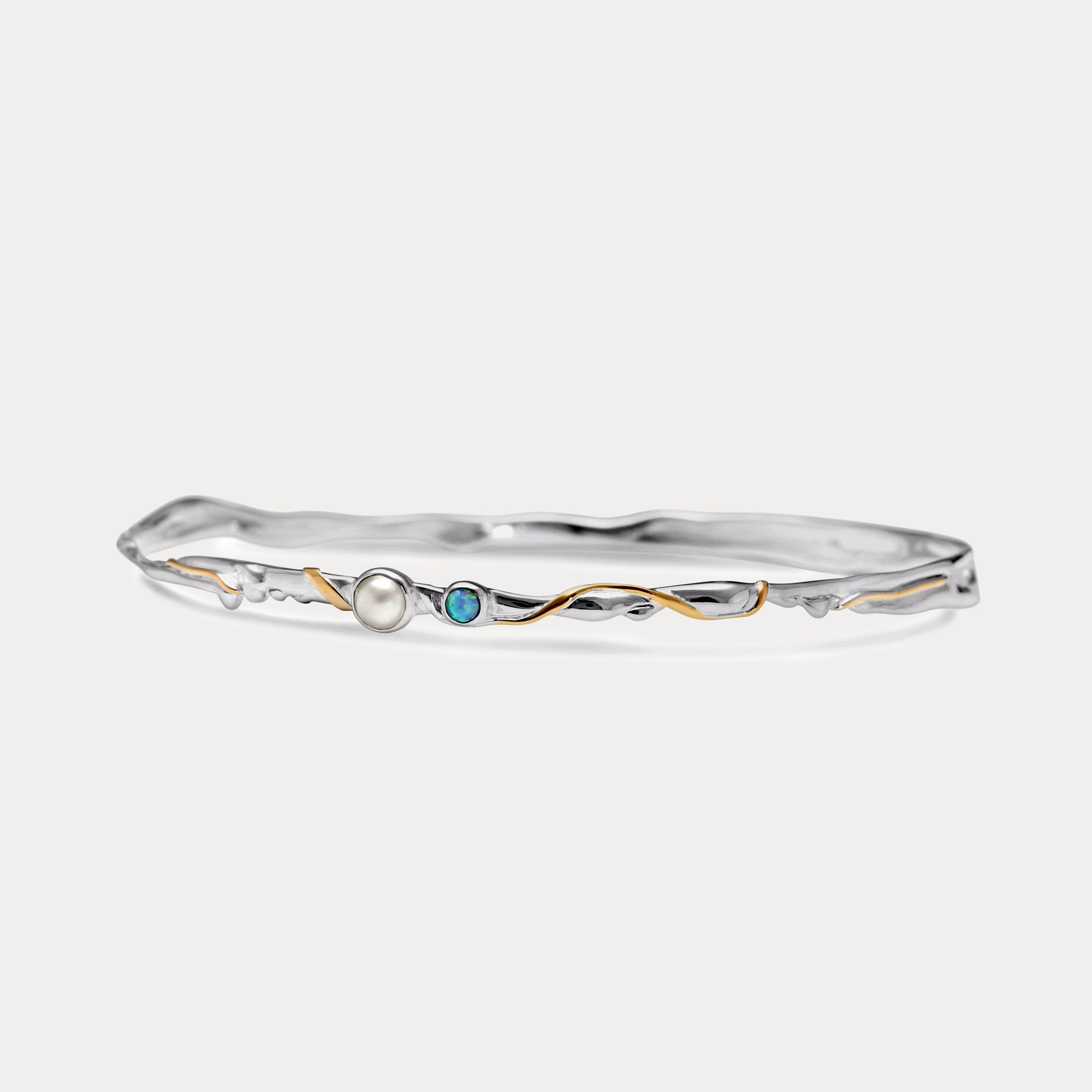 a slim silver bangle with opal and pearl stones and gold details