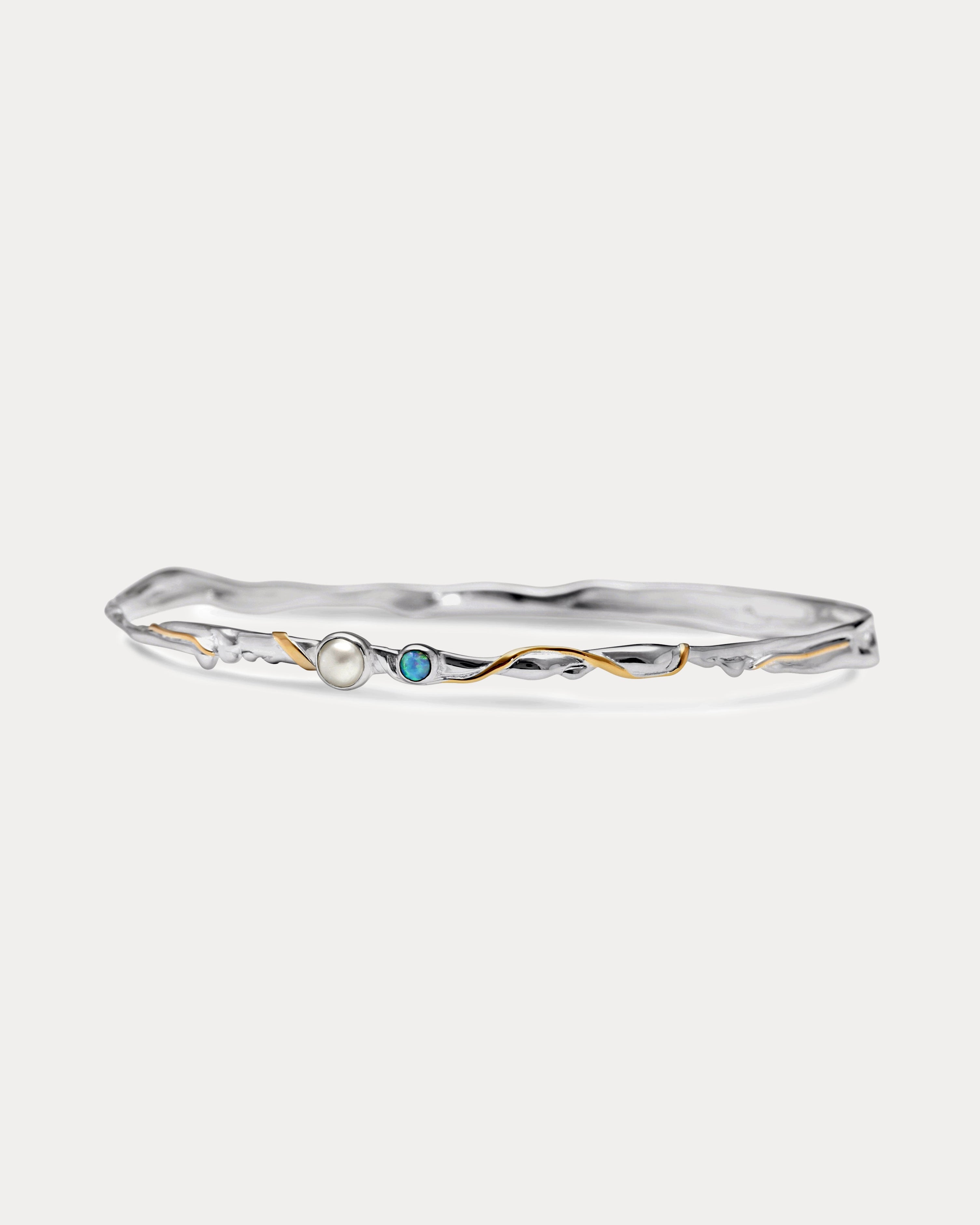 a slim silver bangle with opal and pearl stones and gold details