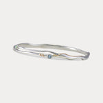 A Sterling Silver bangle bracelet with a small round blue Topaz and white Opal accented by 14KT Gold Fill Wire.