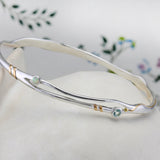 Silver bracelet with blue topaz and white opal on a floral-patterned fabric background