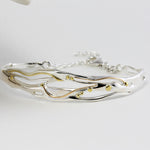 Silver bracelet with gold accents on a white background