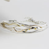 Silver bracelet with gold accents on a white background
