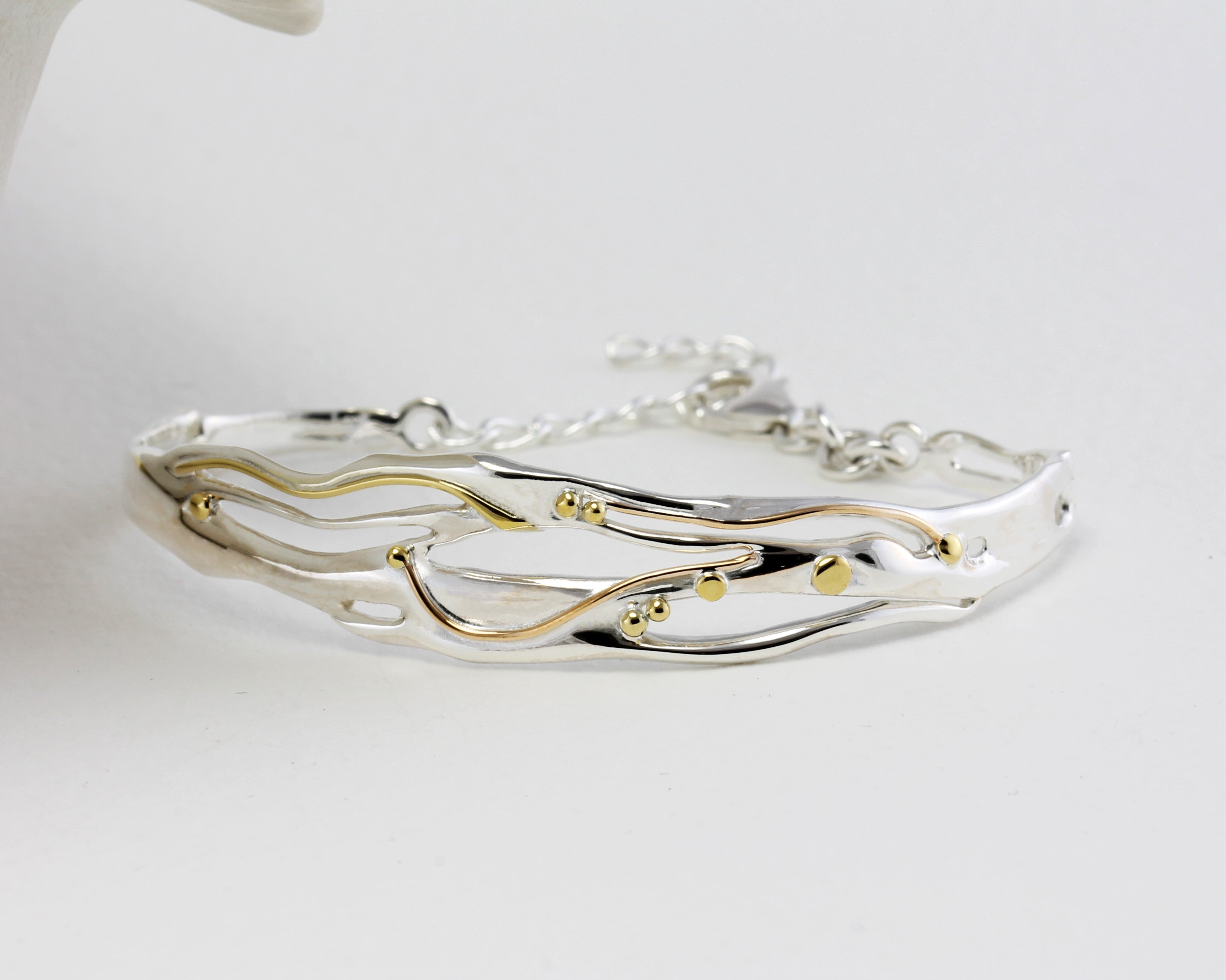 Silver bracelet with gold accents on a white background