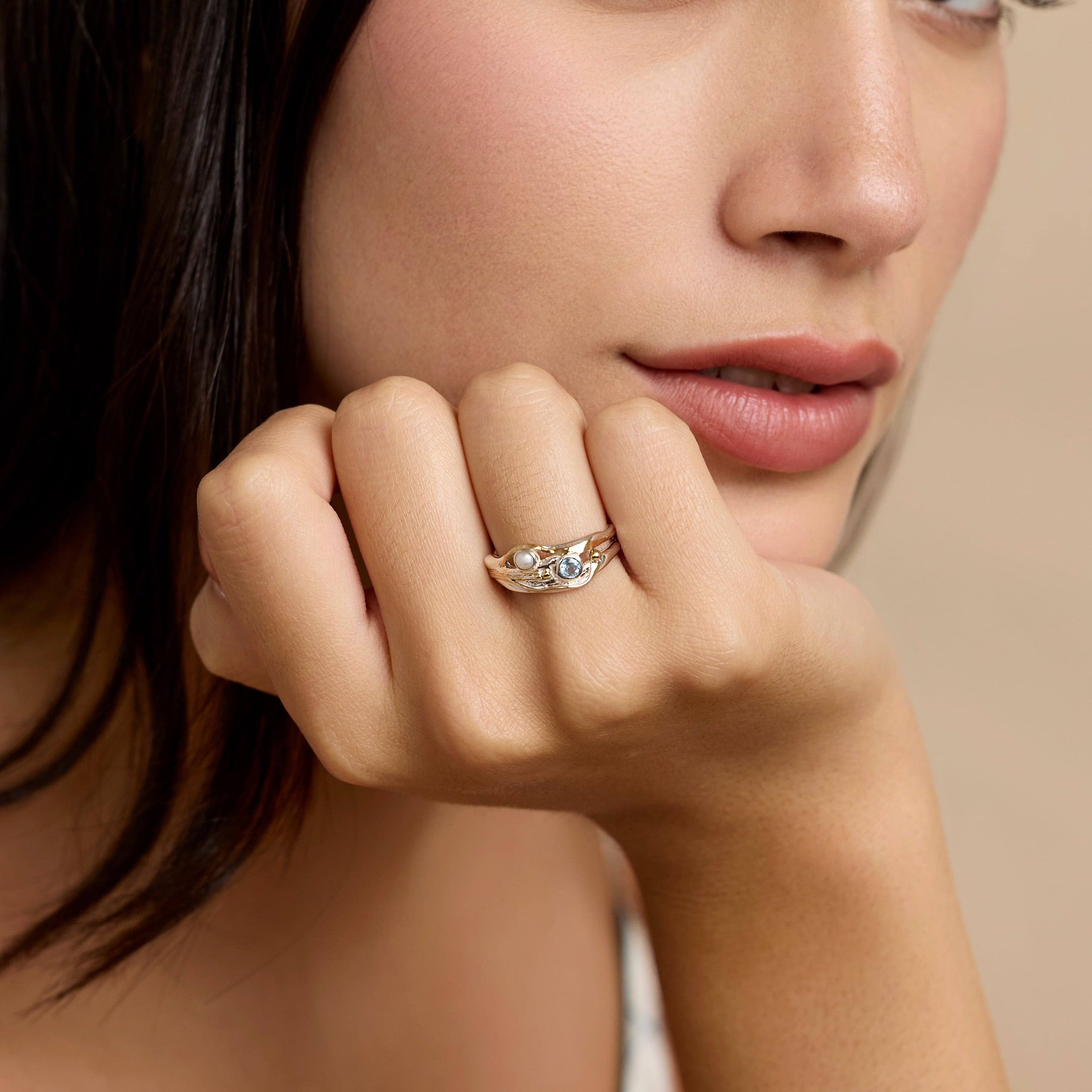 Model wearing silver ring with blue topaz and pearl stones