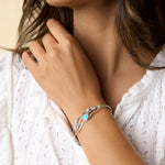 Model wears sterling silver flowing bracelet with brilliant blue Opalite stones