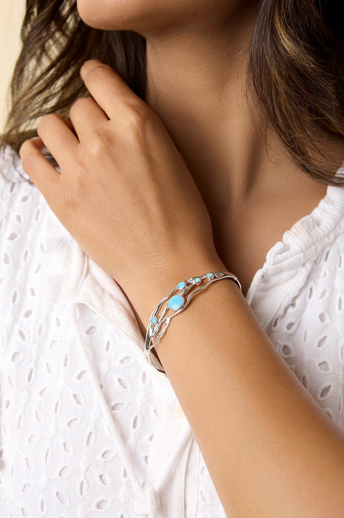 Model wears sterling silver flowing bracelet with brilliant blue Opalite stones