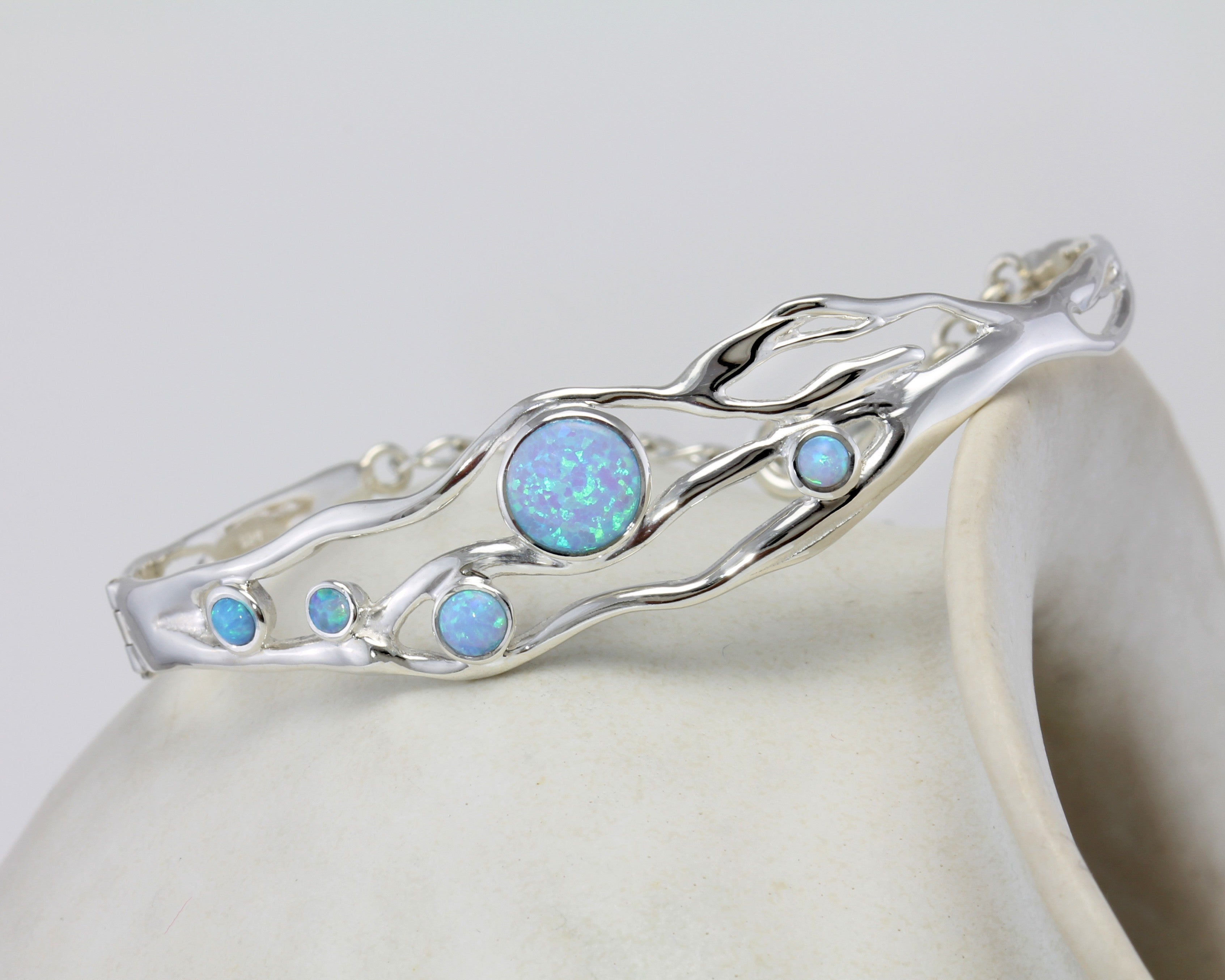 Sterling silver bracelet with five round blue Opals balanced on a pot
