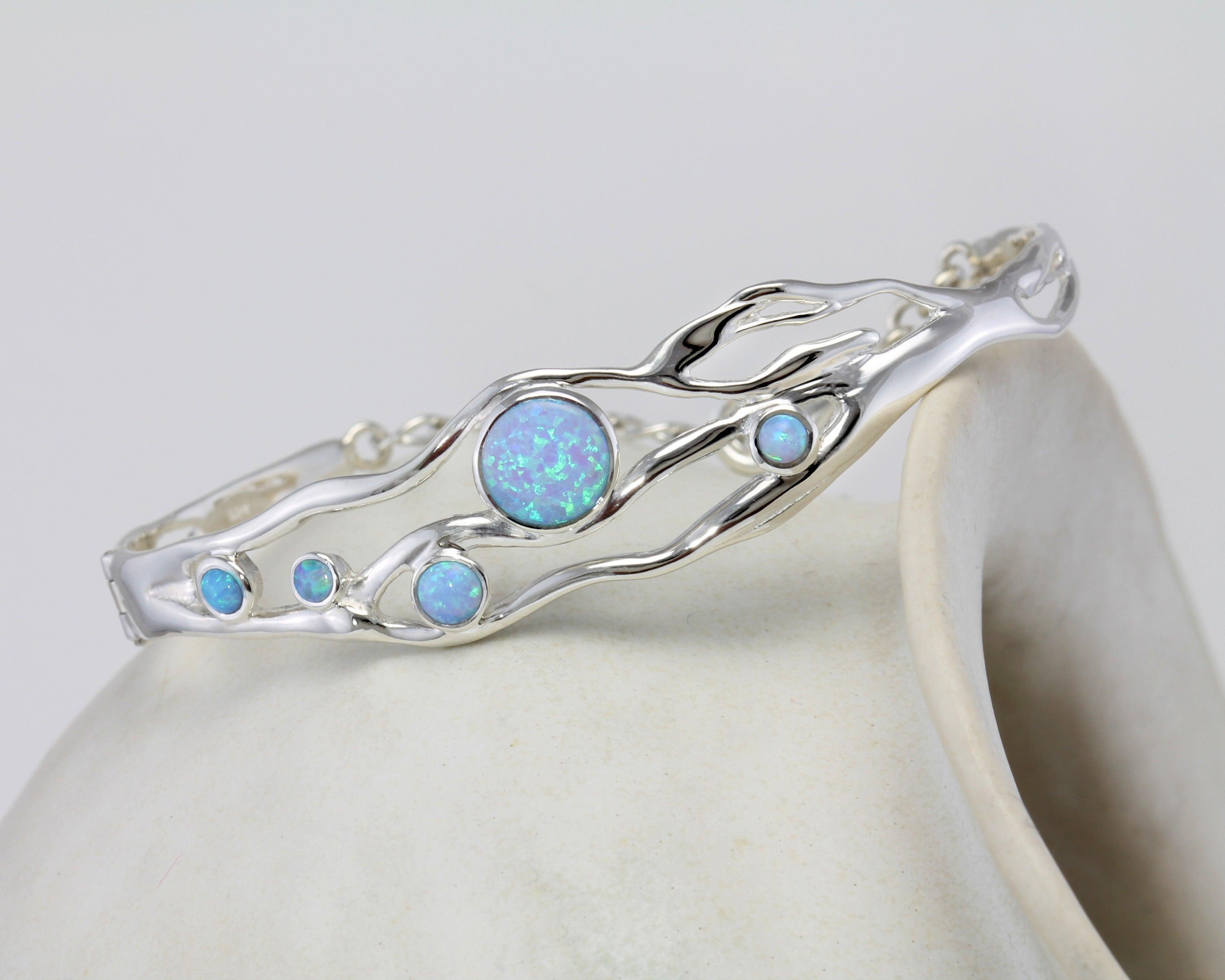 Sterling silver bracelet with five round blue Opals balanced on a pot