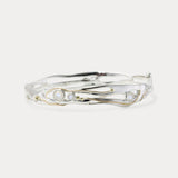 A handmade sterling silver bangle bracelet with moonstone and 14KT gold details, displayed against a white background.