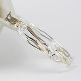 sterling silver bangle leant against ceramic pot with gold detailing and moonstones