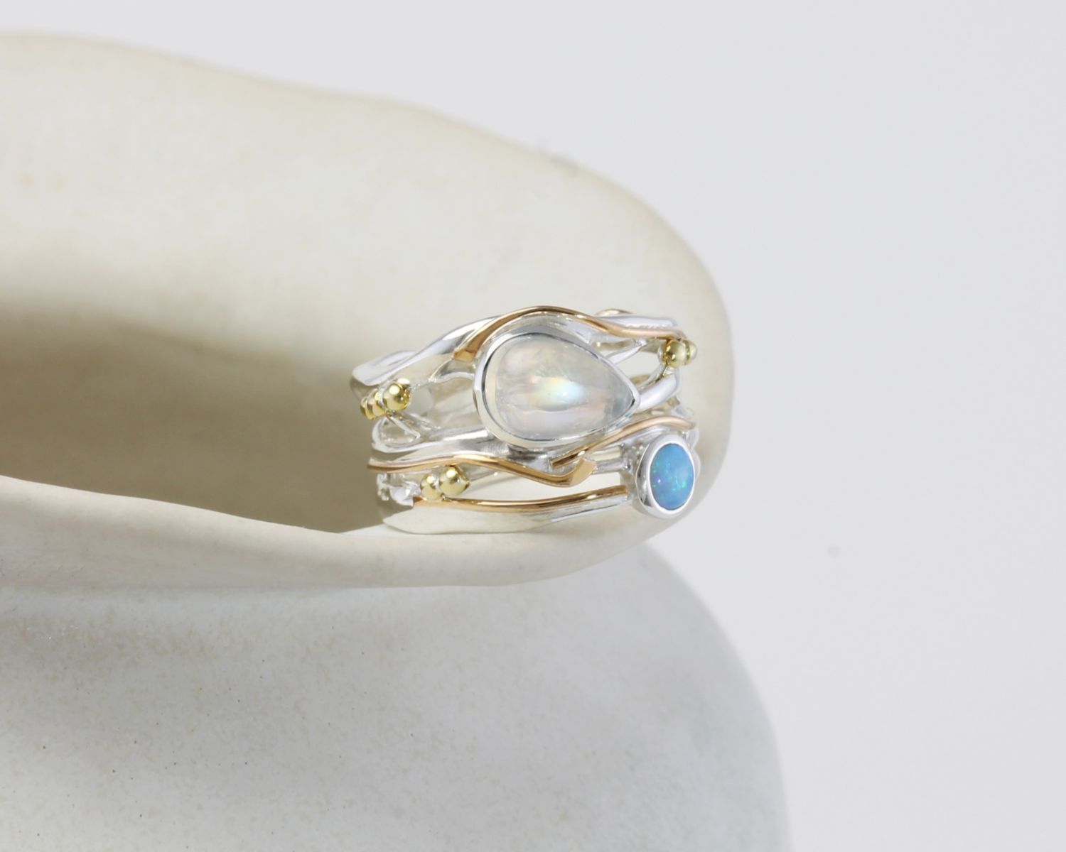 Silver and Gold ring with moonstone and blue gemstone on a white surface