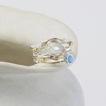 Silver and Gold ring with moonstone and blue gemstone on a white surface