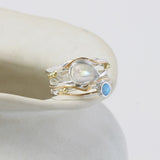 Silver and Gold ring with moonstone and blue gemstone on a white surface
