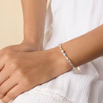 model wearing a delicate sterling silver bangle with blue and white gemstones