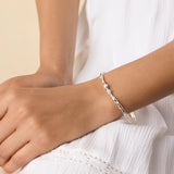 model wearing a delicate sterling silver bangle with blue and white gemstones