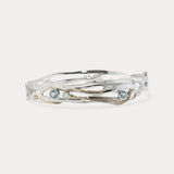 A Sterling Silver bangle featuring round Blue Topaz and a Freshwater Pearl, with 14KT Gold detailing.