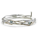 Silver bangle with gemstones and gold details on white background