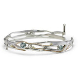 Silver bangle with gemstones and gold details on white background