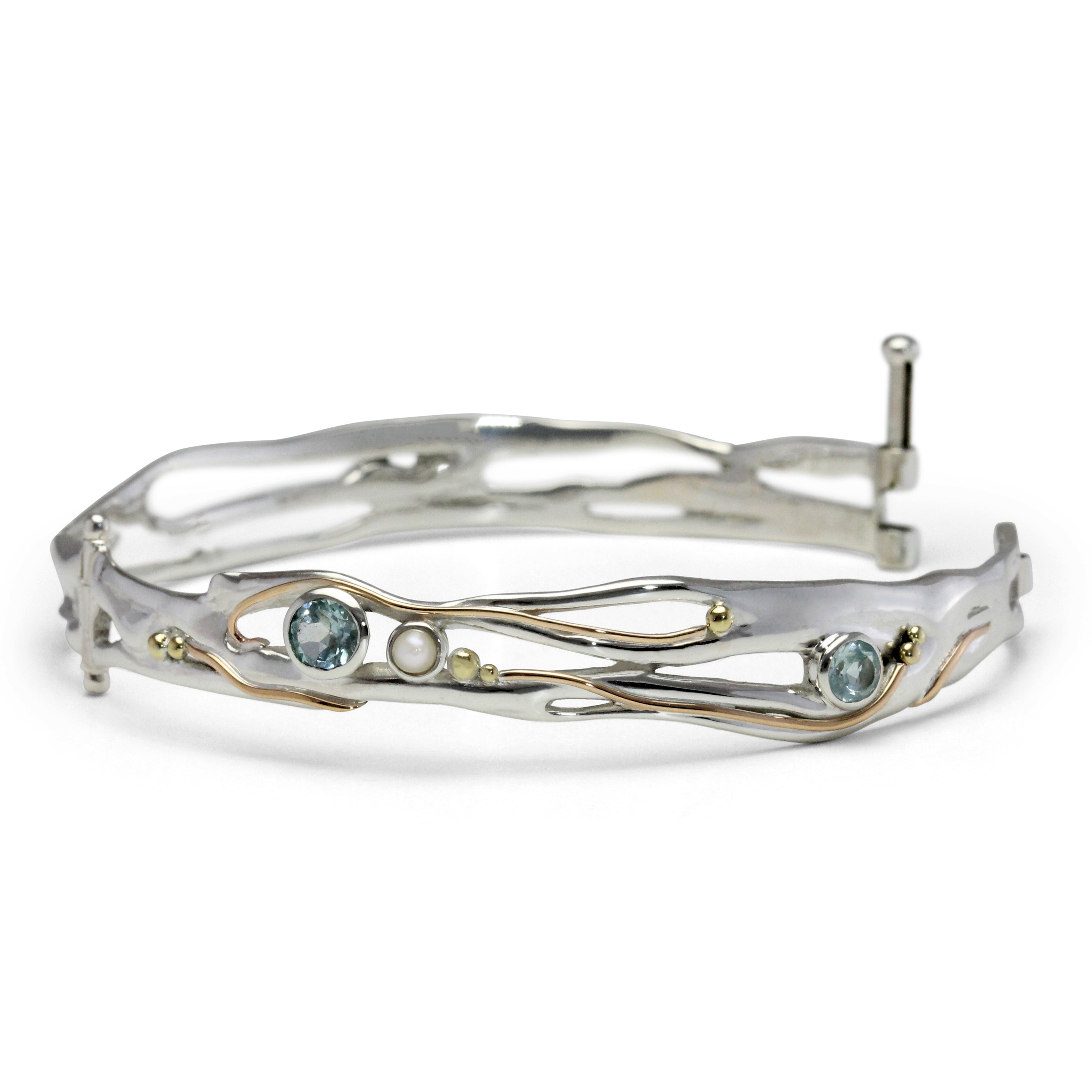 Silver bangle with gemstones and gold details on white background