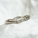silver and gold statement bracelet on a textured stone