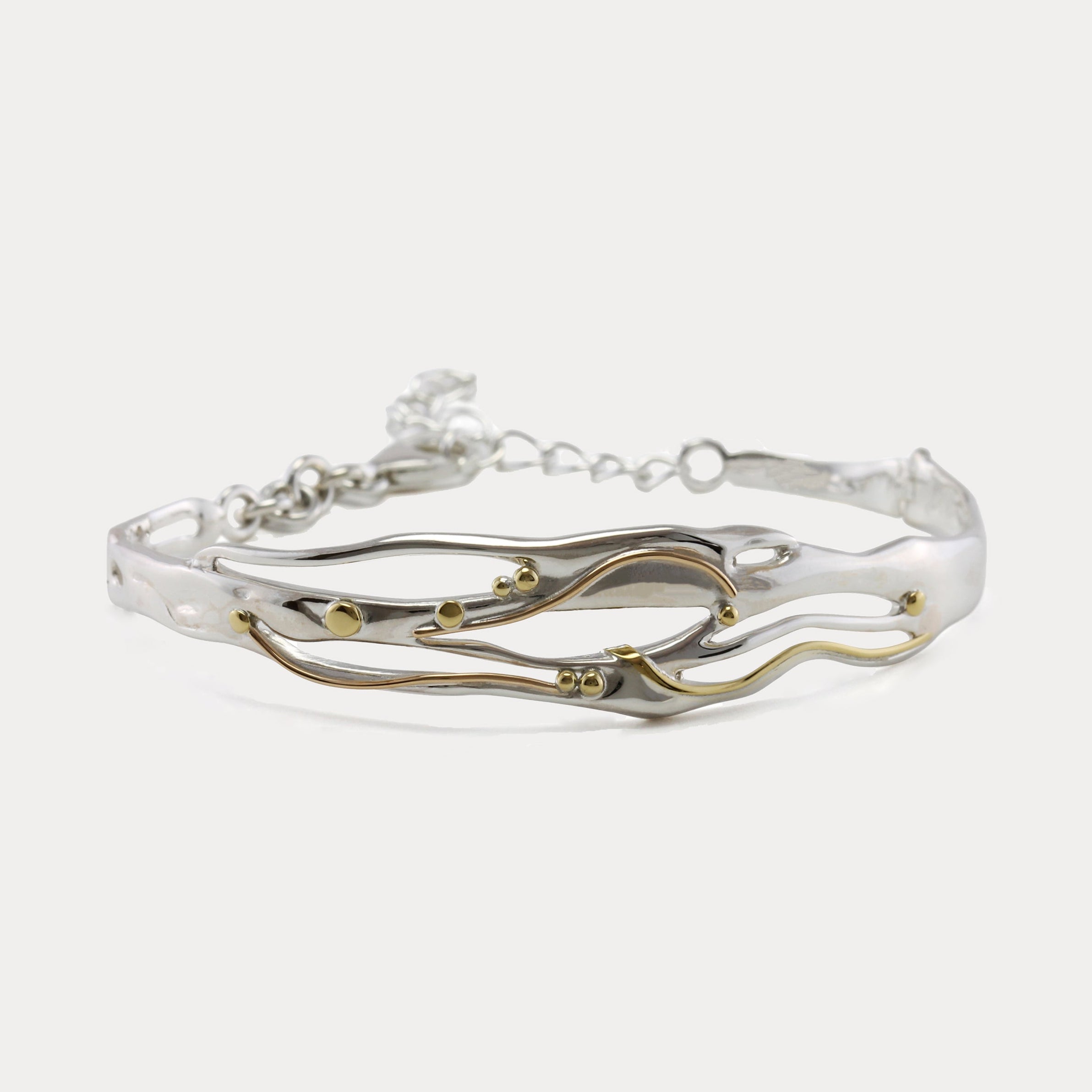 Mixed Metal Bracelet with a flowing design of sterling silver and 14kt gold with brass pip details.