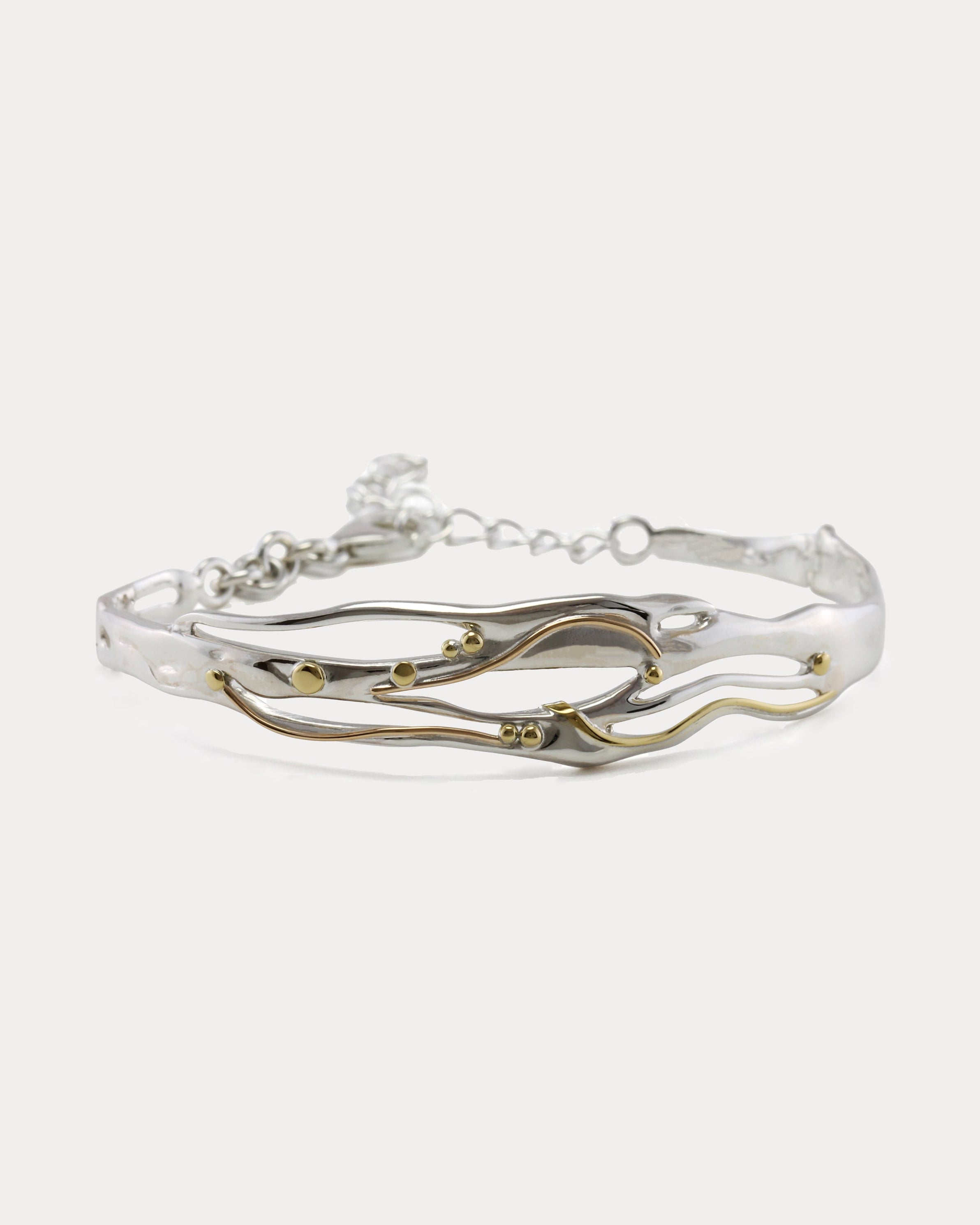 Mixed Metal Bracelet with a flowing design of sterling silver and 14kt gold with brass pip details.