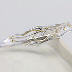 flowing silver and gold bracelet on a ceramic pot