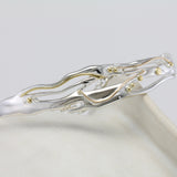 flowing silver and gold bracelet on a ceramic pot