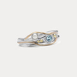A Sterling Silver ring with a faceted Blue Topaz and a Freshwater Pearl, accented with 14kt gold detailing, displayed against a white background.