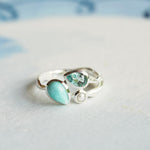 Silver ring with turquoise gemstone on a light blue background