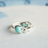 Silver ring with turquoise gemstone on a light blue background