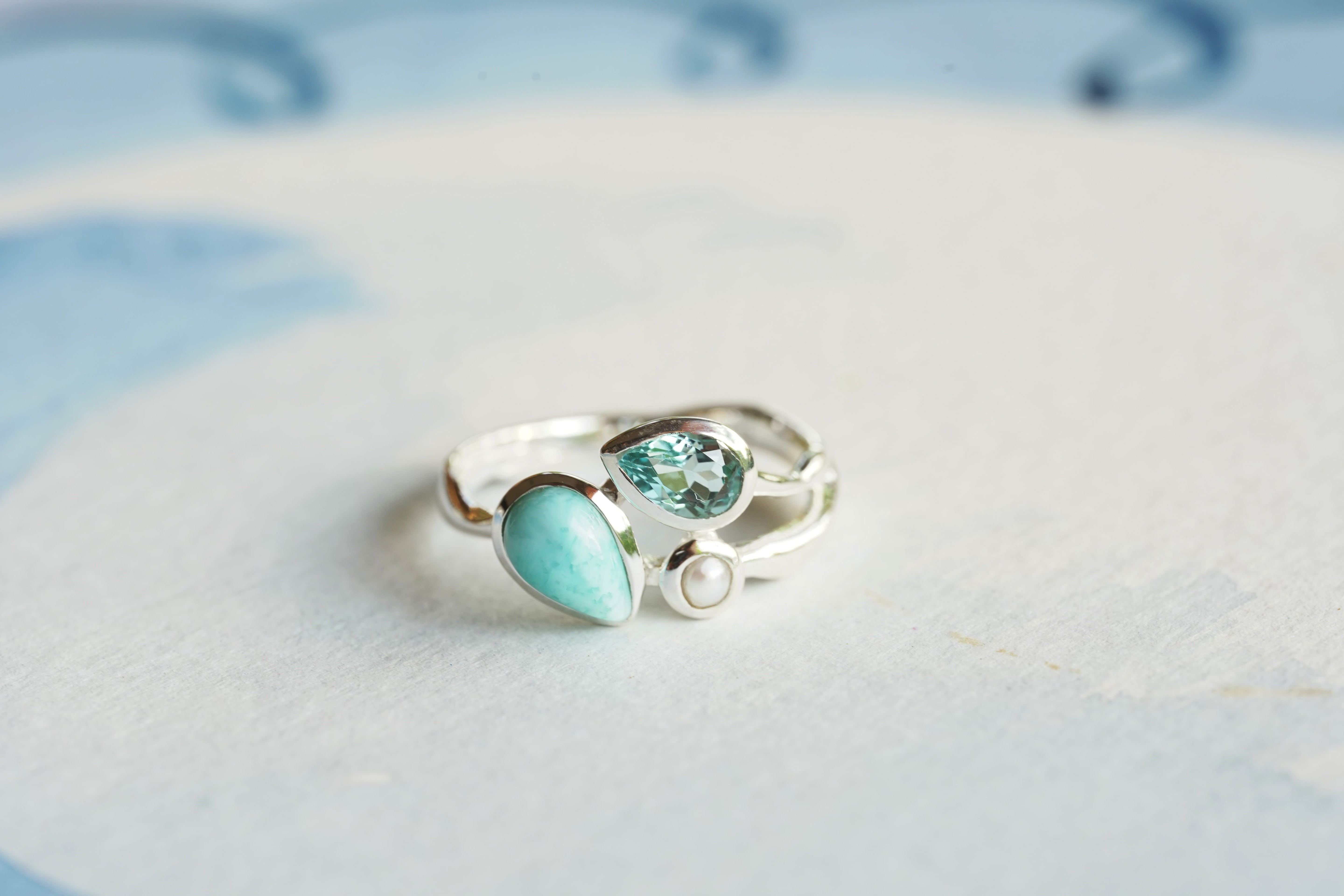 Silver ring with turquoise gemstone on a light blue background