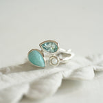 Silver ring with turquoise gemstones on a white fabric background