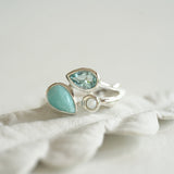 Silver ring with turquoise gemstones on a white fabric background