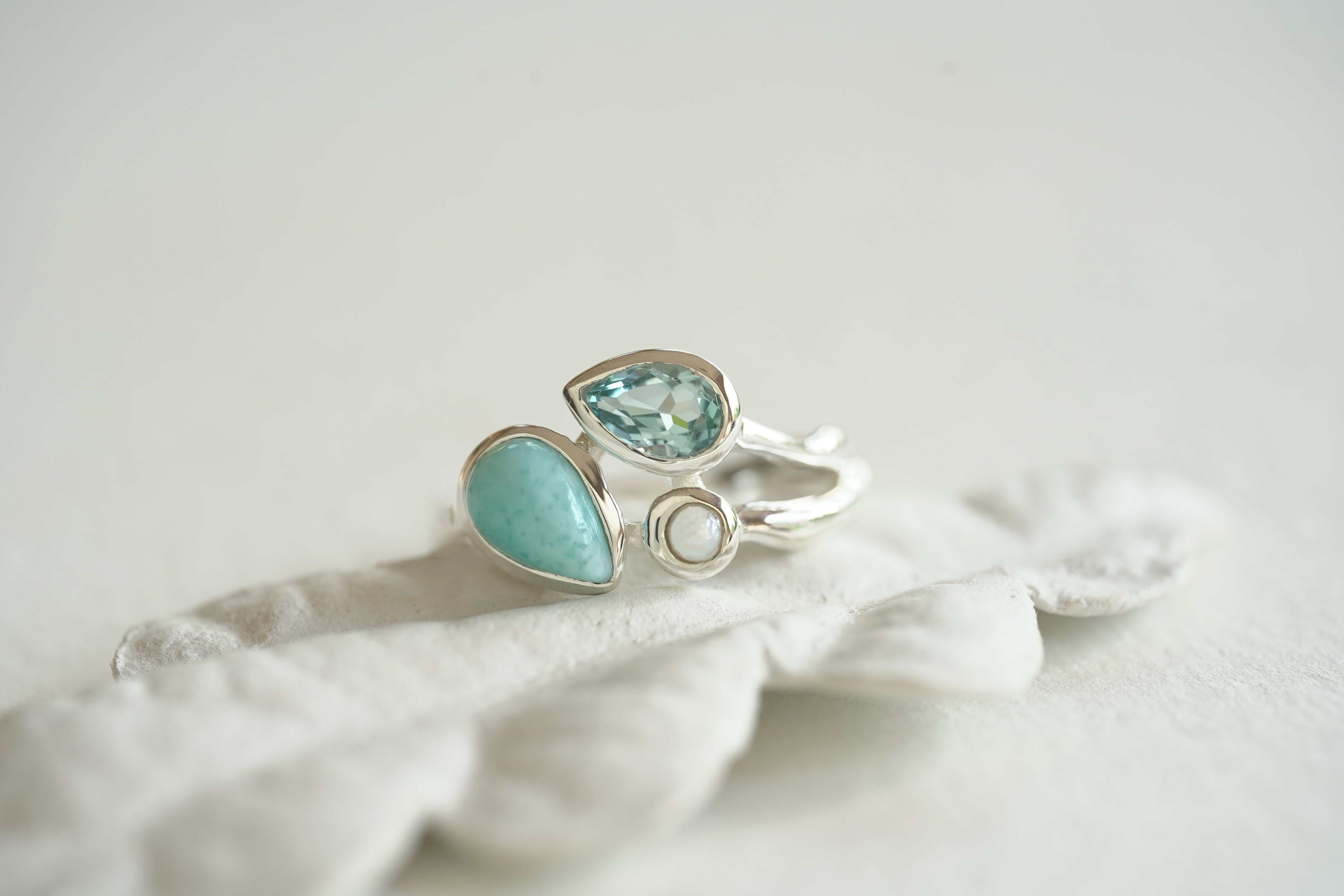 Silver ring with turquoise gemstones on a white fabric background