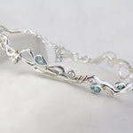Sterling Silver Bracelet with Blue Topaz and Pearl on a ceramic pot