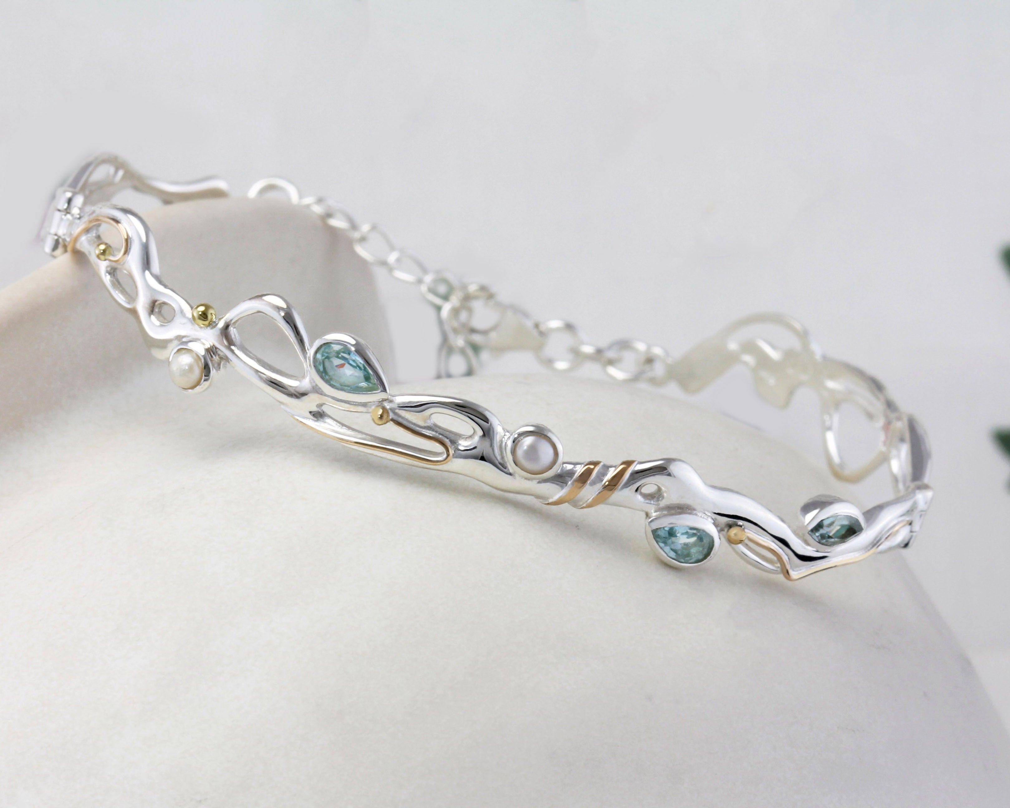 Sterling Silver Bracelet with Blue Topaz and Pearl on a ceramic pot