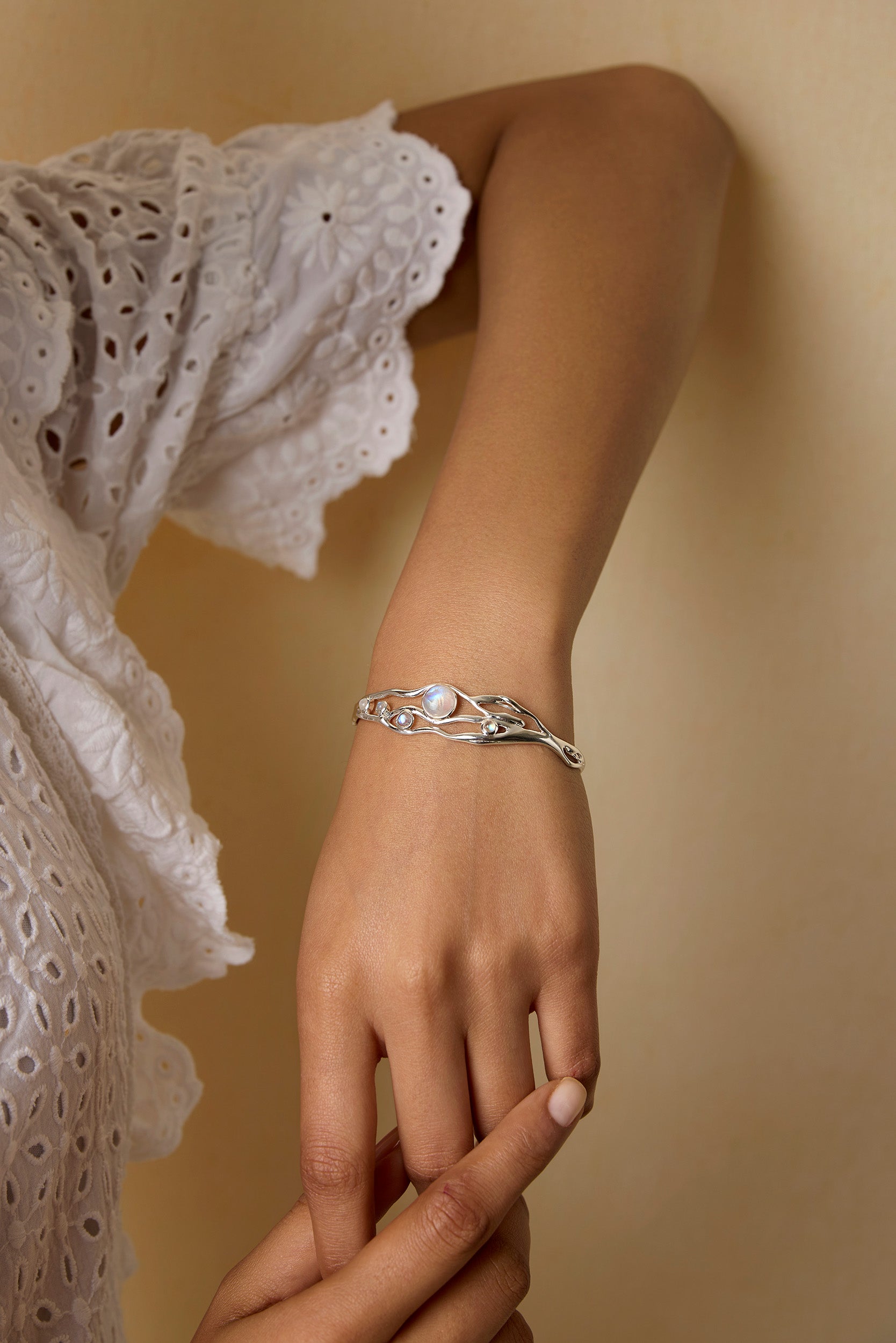 Model leans on wall wearing sterling silver and moonstone bracelet