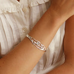 Silver bracelet on a wrist with a white blouse in the background