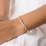 model wearing a delicate silver bracelet adorned with opal and pearl