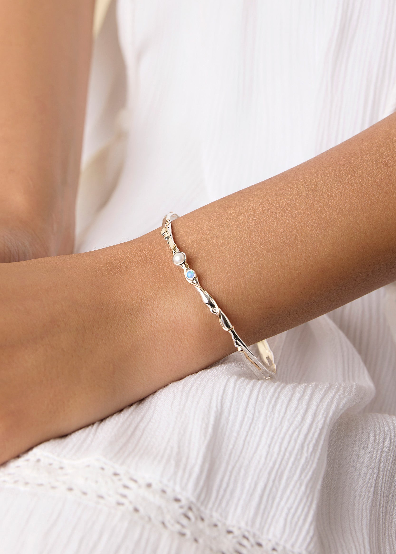 model wearing a delicate silver bracelet adorned with opal and pearl